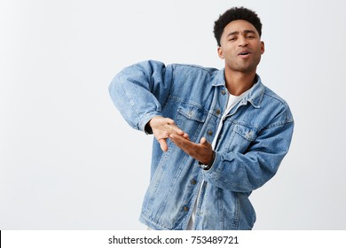 Living rich life. Positive emotions. Portrait of young attractive black-skinned man with afro hairstyle in white t-shirt and denim jacket throwing away money for video clip, having fun with friends.