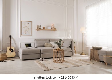 Living Room With Comfortable Grey Sofa, Ottoman And Stylish Interior Elements Near Window