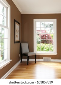 Living Room Corner With Chair And Two Windows And Hardwood Floor.