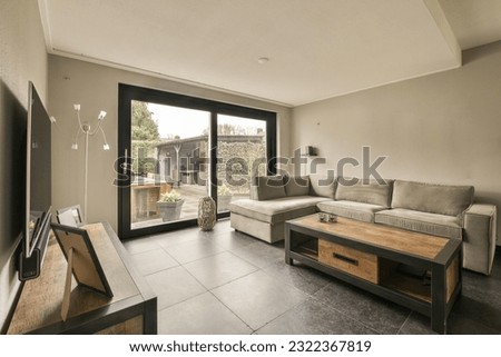 a living room with a couch, coffee table and sliding glass door that opens out to the backyard patio area