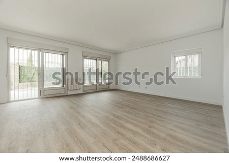 Living room of an empty house with white painted walls, large exit doors 
