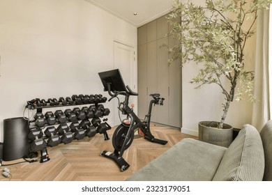 a living room with an exercise bike in front of the tv and other equipment on the wall is painted white