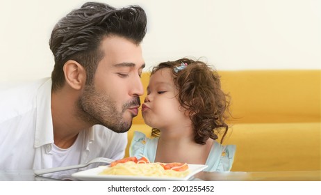 In The Living Room, Father And Daughter Enjoy Eating Spagetti Together. 