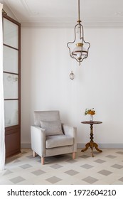 Living Room Interior With Cozy Armchair And Side Table Near White Wall. Retro Style With Vintage Chandelier