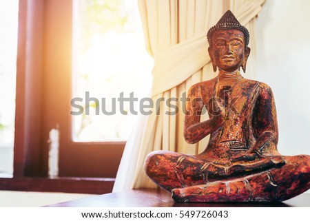 Living room interior decor: buddha statue on the table near the window