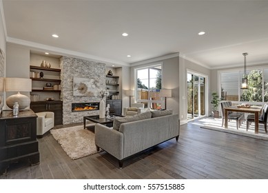 Living room interior in gray and brown colors features gray sofa atop dark hardwood floors facing stone fireplace with built-in shelves. Northwest, USA
 - Shutterstock ID 557515885