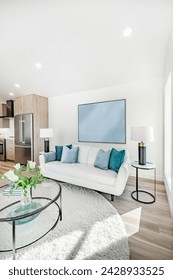 living room interior with white walls aqua blue and green accent colors white sofa large slate grey and black fireplace floor to ceiling windows decorated and staged