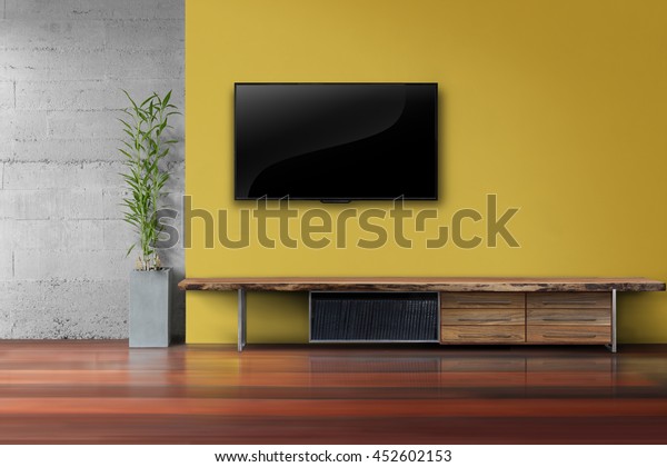 Living room led tv on yellow wall with\
wooden table and plant in pot modern loft\
style