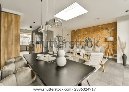a living room with an orange mural on the wall and two white chairs in the center of the room there is a black table
