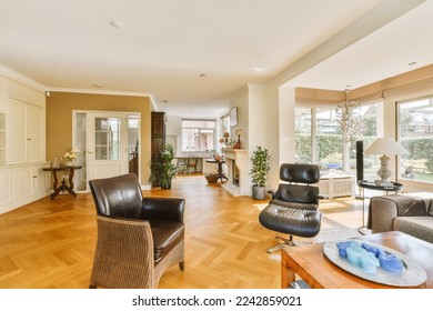 a living room with wood flooring and white trim on the walls, there is an open kitchen in the background - Shutterstock ID 2242859021