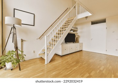 a living room with wood flooring and white painted staircase leading up to the second floor, there is a flat screen tv on