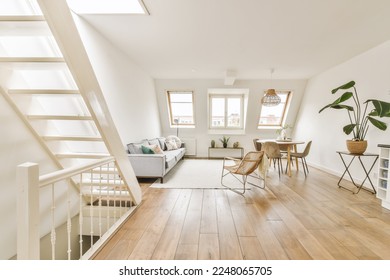 a living room with wood floors and white walls, an open staircase leading up to the second floor is visible