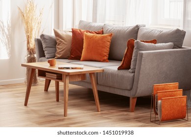 Living Room With Wooden Coffee Table And Grey Couch With Ginger, Orange And Red Pillows