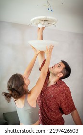 Living Together, Young Man And Woman Install A Ceiling Light, Electrical Cables. Do It Yourself Concept.