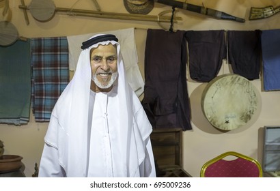 Liwa, United Arab Emirates, July 21st, 2017: Old Emirati Man In A Middle Of UAE Heritage Items