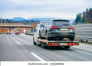 Ljubljana, Slovenia - January 16, 2019: Tow Truck With Car On Warranty In Road. Trailer And Crash Auto Delivery. Vehicles Hauler On Driveway. European Transport Logistics. Heavy Haul Trailer