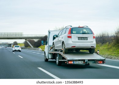 Ljubljana, Slovenia - January 16, 2019: Tow Truck With Car On Warranty On Road. Trailer And Crash Auto Delivery. Vehicles Hauler On Driveway. European Transport Logistics. Heavy Haul Trailer