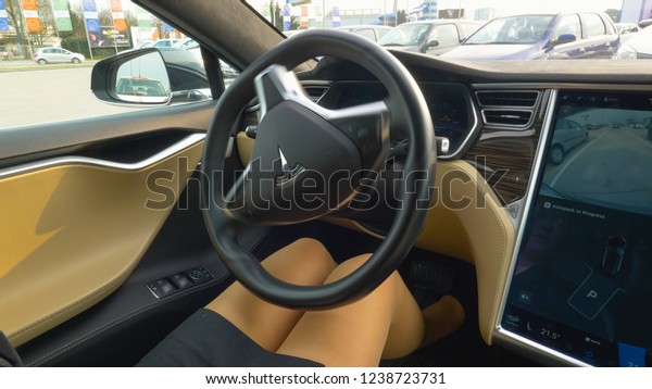 LJUBLJANA, SLOVENIA, MARCH 2018 - CLOSE UP\
Unrecognizable businesswoman sits in the high tech self parking\
Tesla car. Autonomous vehicle parks in reverse without young woman\
holding the steering\
wheel