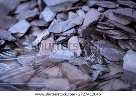 Llayer of ice forming angular patterns over jagged slate rocks