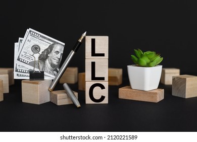 LLC. Limited Liability Company Business Concept Background. Text On Wooden Cubes On Black Background.