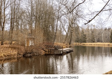 LLittle wooden house and small wooden pier over a calm lake, surrounded by autumn trees with bare branches. The water reflects the sky and foliage, creating a peaceful and serene scene of an autumn pa - Powered by Shutterstock