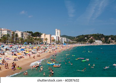 LLORET DE MAR, SPAIN-JULY 8: People swim and sunbathe at the city beach of Lloret de Mar on July 8, 2010 in Lloret de Mar, Spain. The beach is one of the most popular holiday resorts in Spain