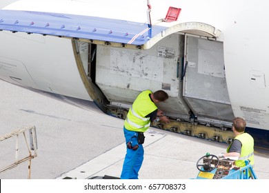 Load of luggage containers in the aircraft cargo compartment. Technicians check the correctness of containers fixing.