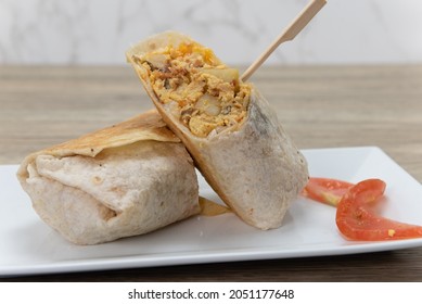 Loaded Breakfast Burrito With Meat And Eggs Cut In Half For Easier Handling.