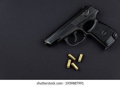 a loaded pistol and its cartridges lie side by side on a black background
