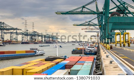 Loaded ships in busy port of Antwerp at container terminal with automated cranes and lots of vessels. Belgium