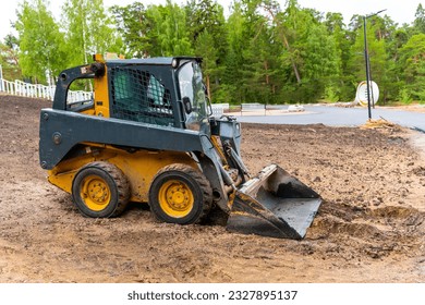  A loader with a bucket clears the site for construction