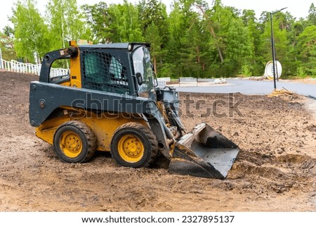  A loader with a bucket clears the site for construction