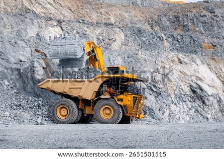 Loader bucket on loading gold ore into mining truck.
