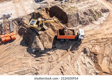 Loader Excavator Loads The Ground In The Truck On Construction Site. Aerial Overhead View.