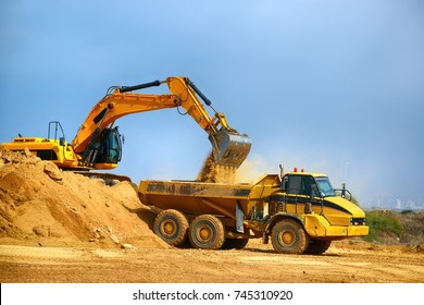 Loader excavator loads the ground in the truck at the road construction