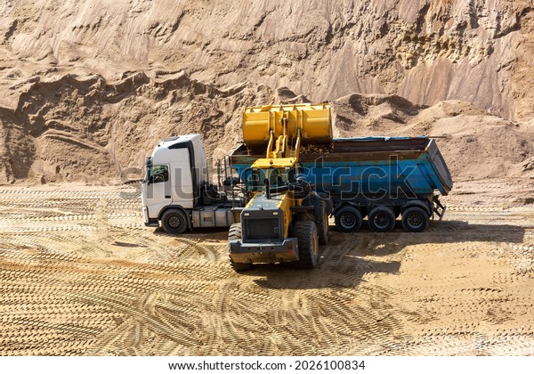 A\
loader loads sand into the car body in a sand\
quarry.