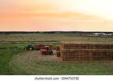 Loader At Unload Round Bales Of Straw From Hay Trailer. Store Hayat Farm. Hay Forage Feed For Beef And Dairy Cattle. Making Hay In Autumn On John Deere Tractor. Russia, Smolensk, Sept 17, 2021