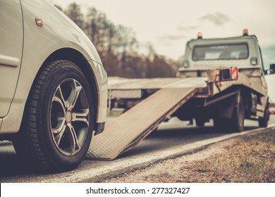 Loading broken car on a tow truck on a roadside 