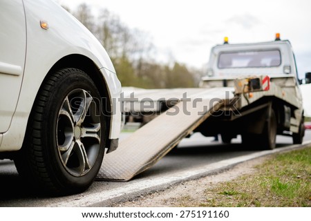 Loading broken car on a tow truck on a roadside 