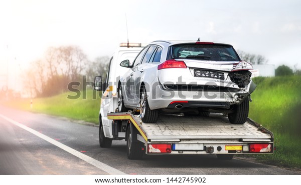 Loading broken car on a tow truck.\
Damage vehicle after crash accident on the highway\
road.