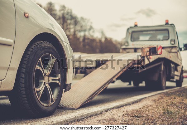 Loading broken\
car on a tow truck on a roadside\
