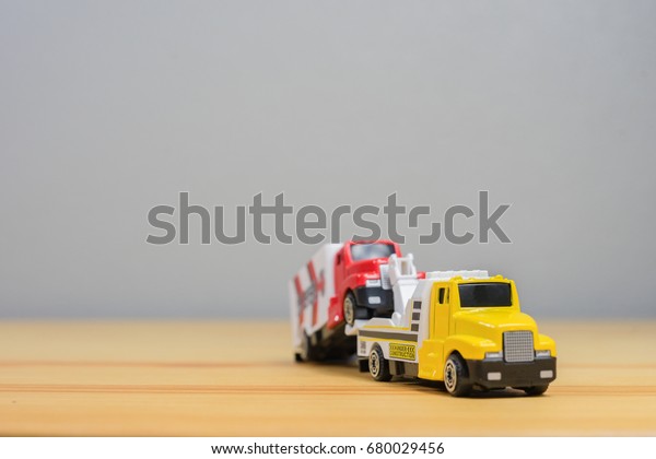 Loading broken toy car on a\
service tow truck  on a roadside after accident on grey\
background.copy space