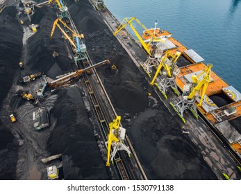 Loading Coal Anthracite Mining In Port On Cargo Tanker Ship With Crane Bucket Of Train. Aerial Top View.