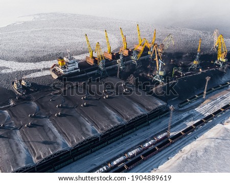 Loading coal mining in port on cargo tanker ship with crane bucket of train. Aerial top view.