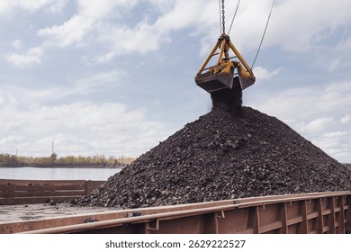 Loading coal using a floating crane onto a barge. Coal is poured from a bucket onto a barge, the Yenisei River.
