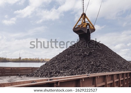 Loading coal using a floating crane onto a barge. Coal is poured from a bucket onto a barge, the Yenisei River.