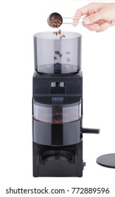Loading coffee grinder with coffee beans by spoon, stages of coffee making, isolated on white background