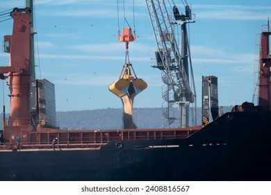 Loading dry cargo ship of wheat by cranes in port. Loading into holds of sea cargo vessel