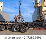 Loading of hot rolled steel coils on board of cargo ship using braided wire slings and heavy crane.