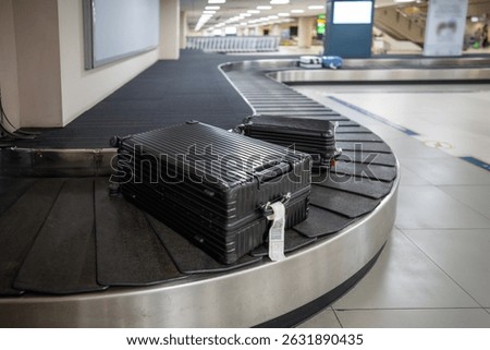 Loading luggage moving on baggage conveyor belt during post flight unloading. Travel bags advance toward claim area, passengers wait for returning items